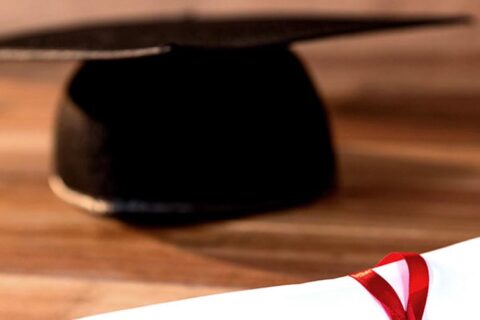Close-up of graduation certificate with mortar board on a table