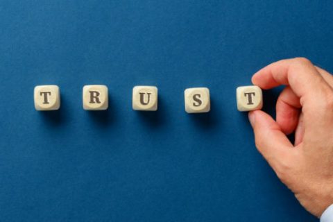 Businessman assembling the word trust with wooden dices