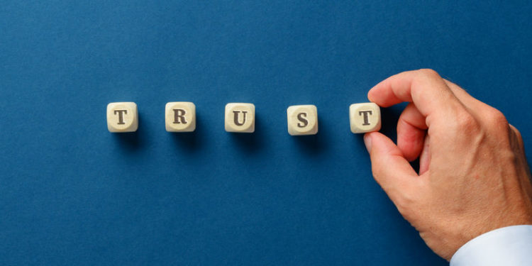 Businessman assembling the word trust with wooden dices